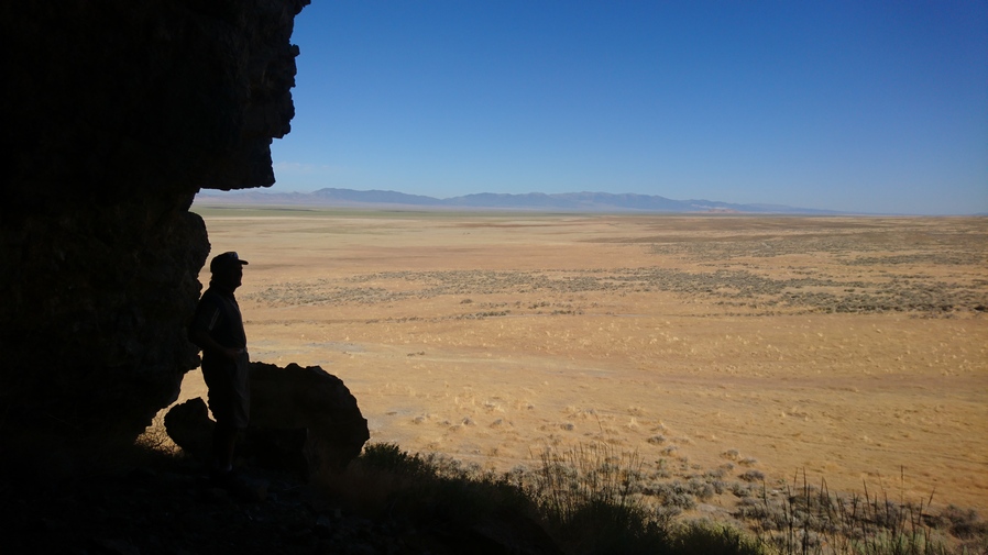 man standing in the shadows of a small cave overlooking goshute valley