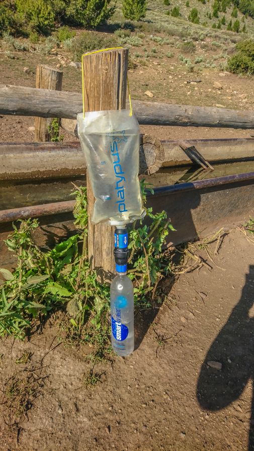 hiker makes diy gravity feed water filtration system on trail