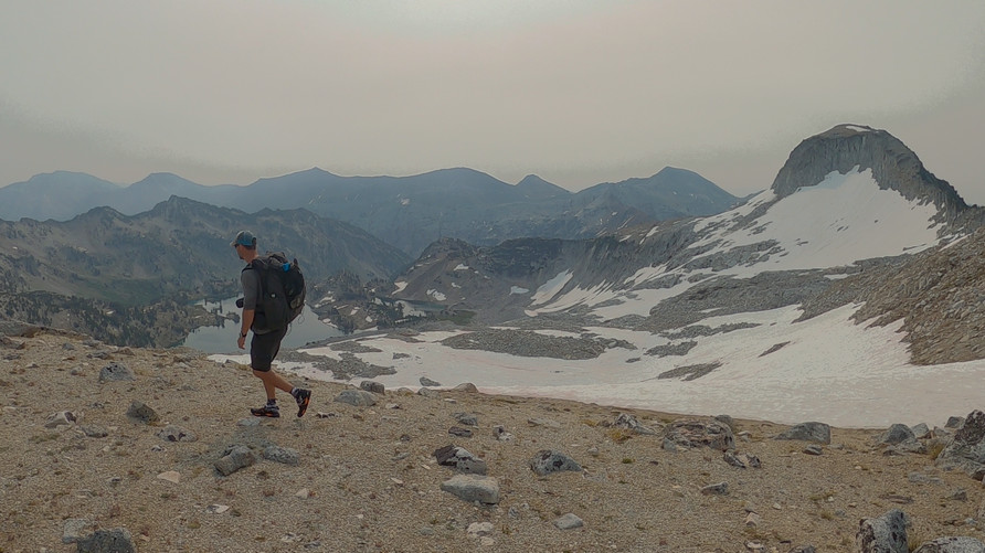 hiker walking the crest of the wallowa mountains with forest fire smoke 